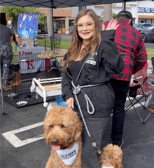 Volunteer with golden doodle at event.