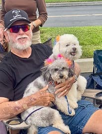 Older man holding two fluffy dogs.