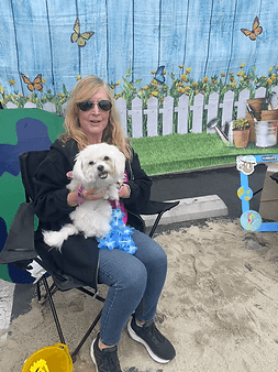 Woman holding a small white doodle at an event.